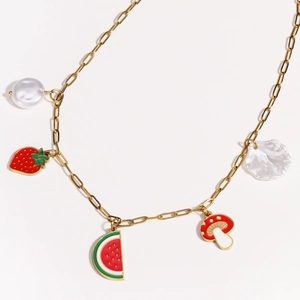 Detailed close-up of gold chain necklace featuring fruit, mushroom, and shell pendants