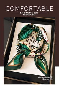 Detailed view of dark green polka dot silk scarf with gold borders in premium gift box