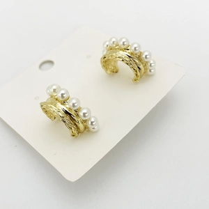 Golden C-shaped earrings with linear pearl accents and wavy textured metal surface