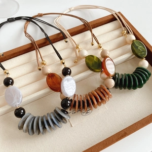 Detailed view of layered leather necklaces with oval pendants in assorted earth tones