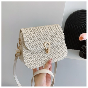 Close-up of cream woven texture handbag with golden horseshoe buckle and strap