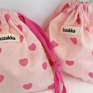 Detailed view of pink canvas drawstring bags with heart pattern and Sozakka woven label