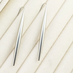 Close-up of silver teardrop dangle earrings on a velvet display, polished metal texture