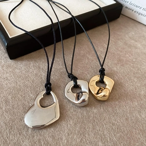Close-up of heart and liquid metal pendants on thin black cords for layered necklaces