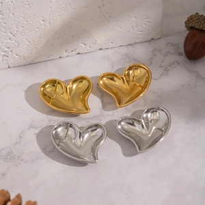Close-up of gold and silver puffy heart studs on a white marble background