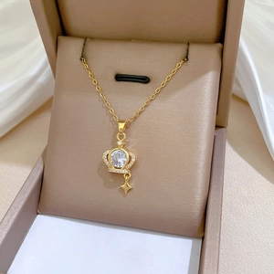 Macro shot of gold crown pendant necklace with large zircon and star charm in a jewelry box