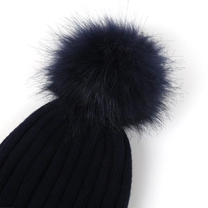 Détail d'un bonnet en maille bleu foncé avec un pompon en fausse fourrure pour l'hiver