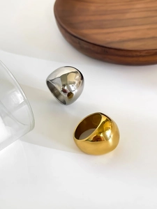 Polished 18K gold and silver chunky dome rings on a minimalist wooden tray display