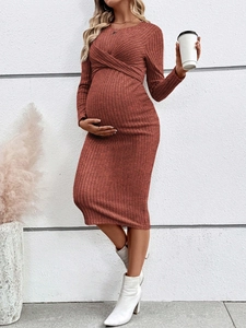 Close-up of rust-red maternity knit dress featuring ribbed texture and crossover front