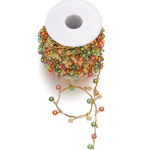 Macro detail of colorful daisy charms on a gold chain roll for DIY jewelry making