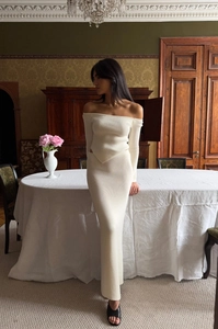 Detail of cream knit set featuring off-shoulder top with asymmetrical hem and long skirt