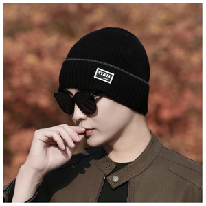Detail of black winter knit beanie featuring a white branded patch and thick ribbed texture