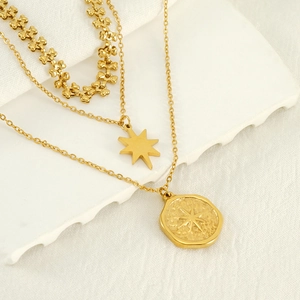 Vintage triple-layer stainless steel necklace with star pendants on white linen backdrop