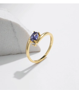 Detail of gold ring featuring oval purple gemstone and small clear side stones