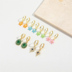 Retro gold earrings set with colorful enamel flowers and green gems on stone background