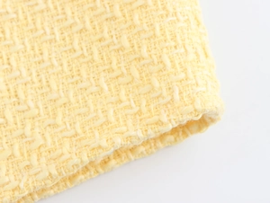 Macro close-up of premium yellow tweed fabric texture showing detailed woven pattern