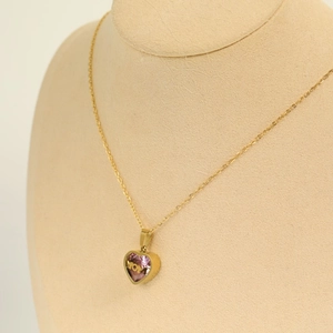 Detailed view of gold MOM necklace with heart pendant and pink zircon on mannequin stand