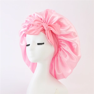 Detailed close-up of pink satin hair bonnet showing the silky texture and large bowknot