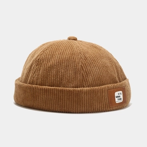 Detailed shot of brown corduroy docker cap featuring a leather logo patch on the brim