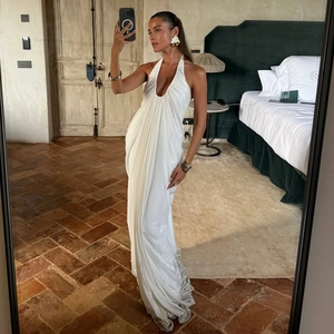 Detail of white pleated halter maxi dress with a deep V-neck and elegant draped texture