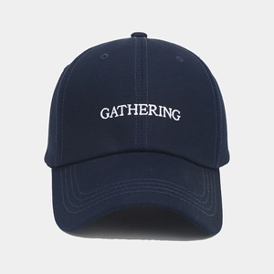 Gros plan détaillé de la broderie blanche GATHERING sur casquette en coton marine