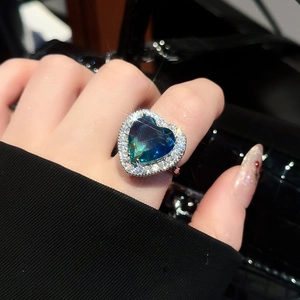 Detail of a heart-shaped ring with blue-green gradient stone and sparkling zircon halo