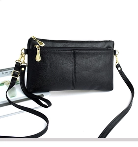 Close-up of black lychee-textured leather crossbody bag with golden metal zipper detail