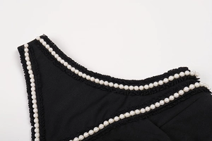 Macro detail of black lace fabric with white pearl trim on a sleeveless evening dress