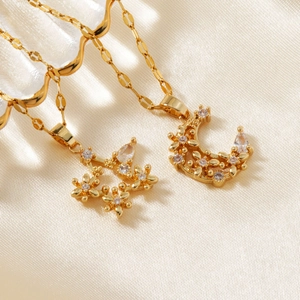 Detailed close-up of gold star and moon pendants with zircons on soft cream silk fabric