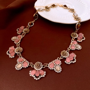 Macro shot of vintage style gold necklace with pink gems and rhinestones on brown fabric