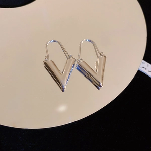 Détail macro de boucles d'oreilles géométriques en V argentées avec une finition miroir polie