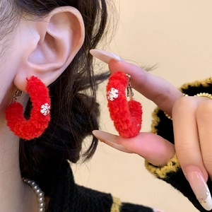 Detail of red flocked circular earrings with snowflake charms worn for a festive look
