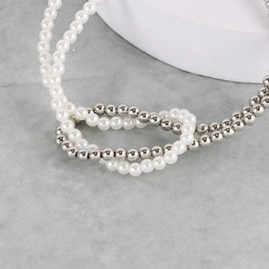 Macro shot of faux pearl and silver metal beads knotted necklace detail on marble
