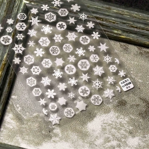 Close-up of Japanese style ice crystal snowflake nail art stickers on a textured background