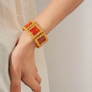 Close-up of vintage golden bracelet with square links and red enamel spiral detail