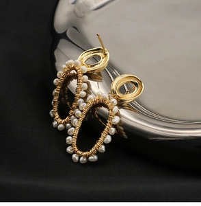 Detail of natural pearls hand-wired onto oval gold metal frames on luxury earrings