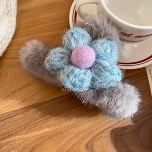 Detail of plush faux fur hair claw with a blue knitted flower and purple wool accent