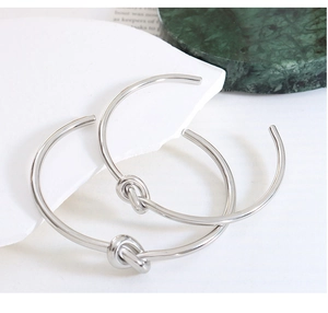Close-up of polished silver knotted open cuff bracelet on elegant marble display stand