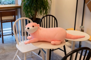Pink otter plush toy with soft fur lying on a white table in a cozy indoor setting