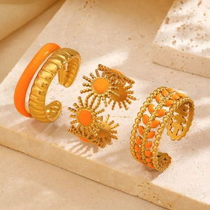 Three-piece gold-plated stainless steel ring set with sunburst and orange enamel accents