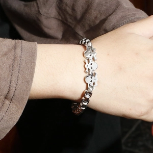 Close-up of punk style men's silver skull bracelet with square chain link on wrist