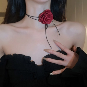 Detail showing a large red fabric rose choker worn by a woman with an off-shoulder top