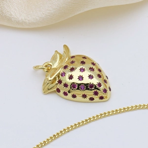 Detailed close-up of a golden strawberry pendant necklace with red star-shaped gemstones