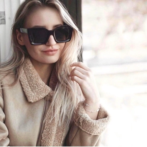 Fashionable black square oversized sunglasses worn by a model in a warm fuzzy jacket