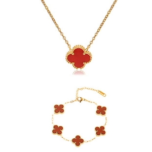 Macro detail of a classic four-leaf clover jewelry set with gold edging and red inlay