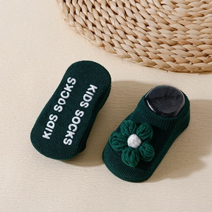 Detail view of green baby floor socks with 3D floral accent and non-slip grips