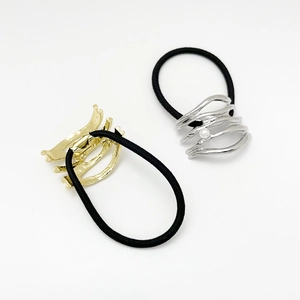 Detail of black elastic hair rings with gold and silver alloy accents and a small pearl