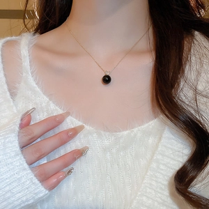 Detailed view of black pearl pendant with diamond detail on a minimalist gold chain