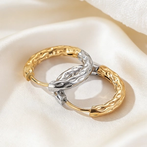 Two-tone hammered steel hoop earrings with gold and silver finish on silk fabric