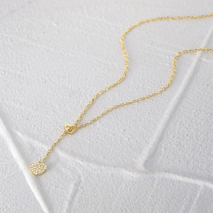 Detail of gold double heart necklace with crystal paving on stone texture background